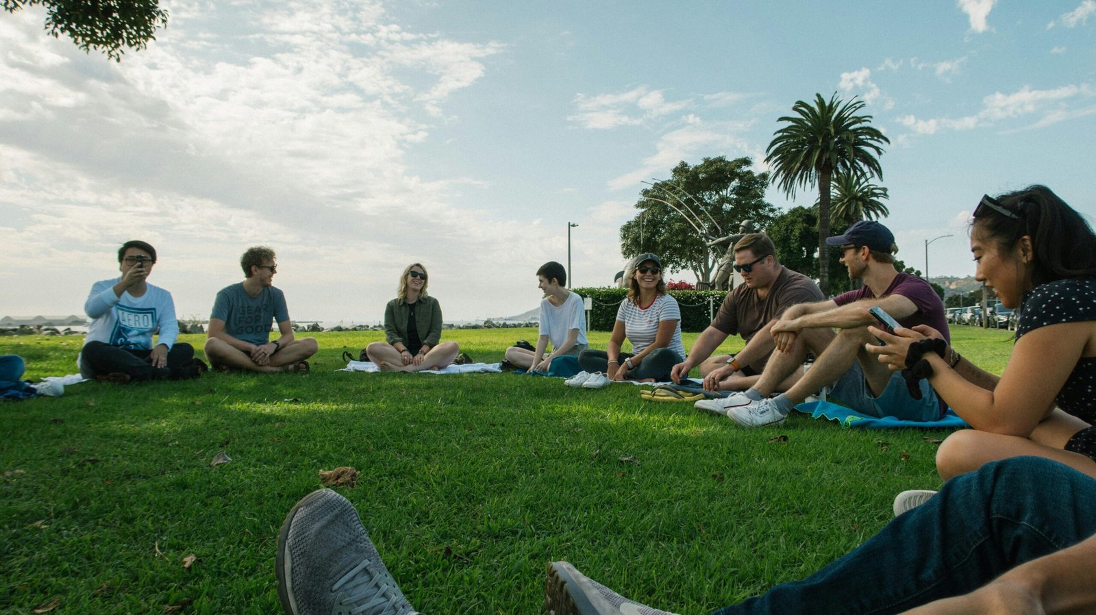 A group of friends sitting together on a sunny day in a green park.